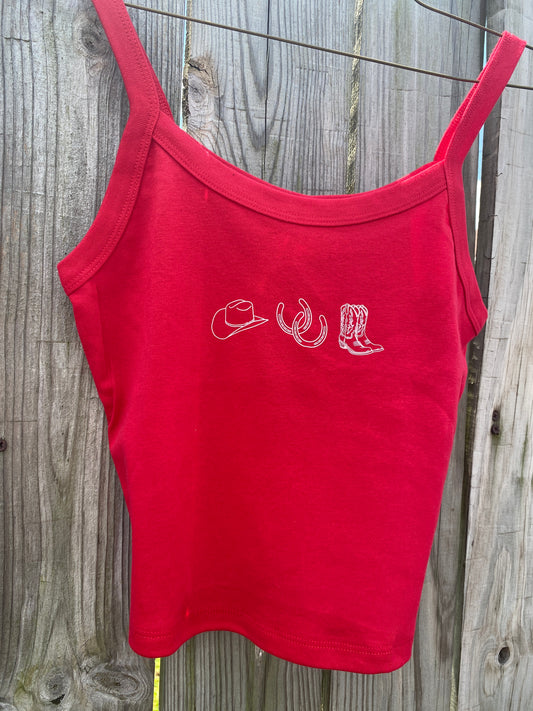 Red tank top with white cowgirl hat, horseshoes, and cowgirl boot graphics on a wooden surface