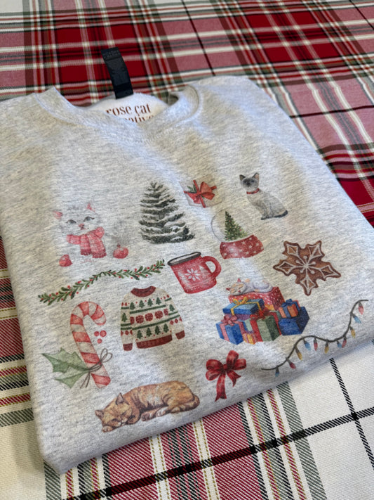 folded ash gildan 18000 christmas cat collage crewneck on red plaid background, watercolor holiday cat illustrations sweater, aesthetic product flat lay for cat lover christmas gifts, soft cozy winter cat sweatshirt with artistic watercolor cats