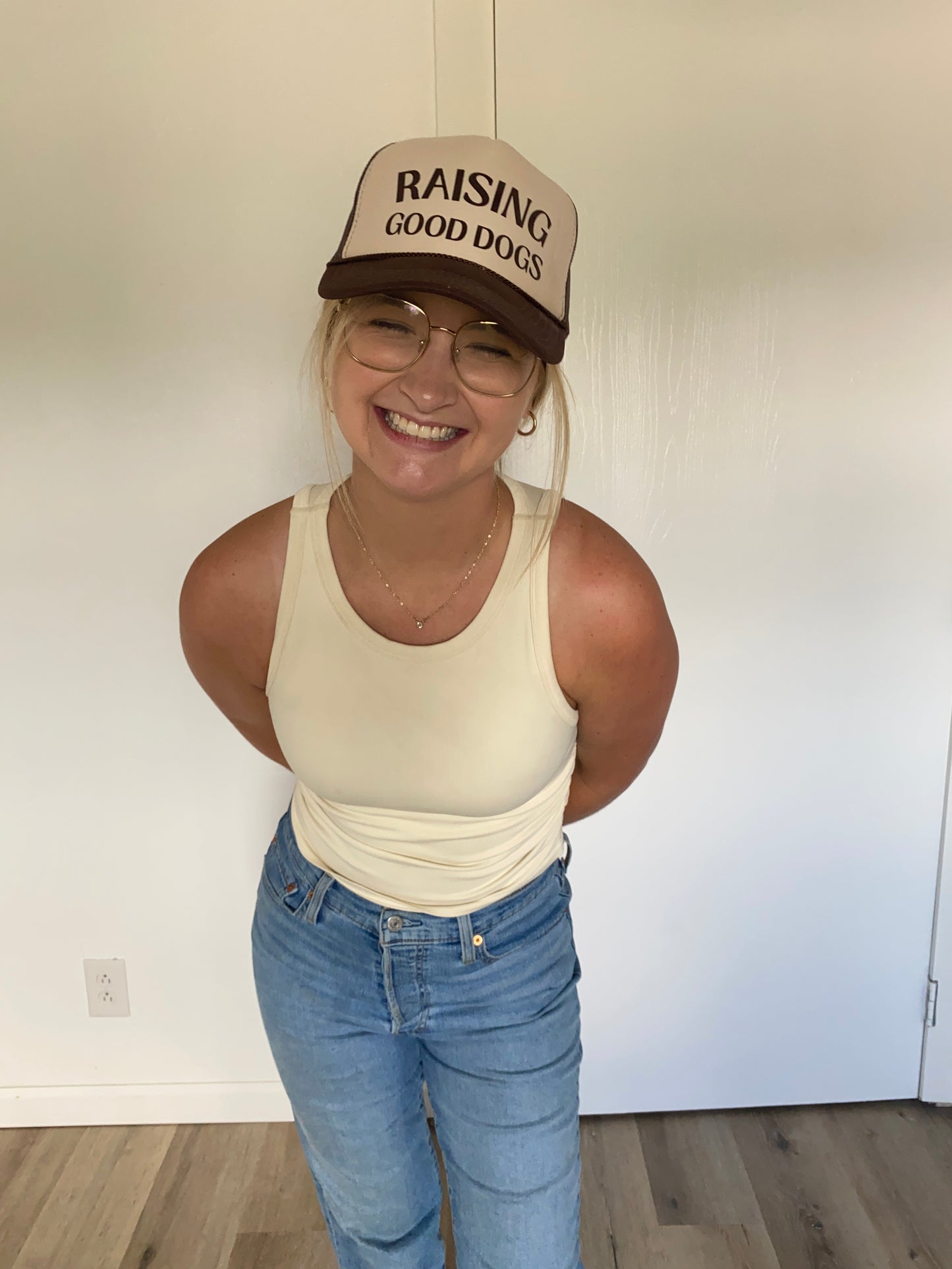 Person wearing a cap with 'Raising Good Dogs' text, smiling indoors.