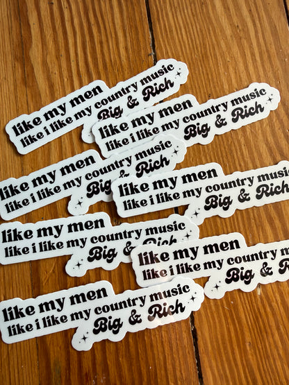 Multiple country music quote stickers laid flat on a rustic wooden surface, each reading “I like my men like I like my country music, Big & Rich.” These durable waterproof vinyl stickers are perfect for laptops, tumblers, phone cases, guitars, and notebooks. A great gift for country music fans, western lifestyle lovers, Nashville souvenirs, and funny southern sticker collections.