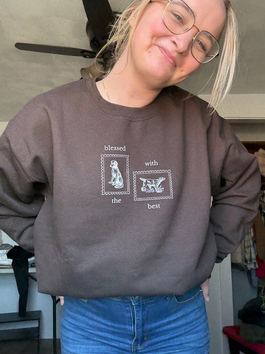 Person wearing a dark brown sweatshirt with Blessed with the Best text and dog stamp graphics, standing indoors.