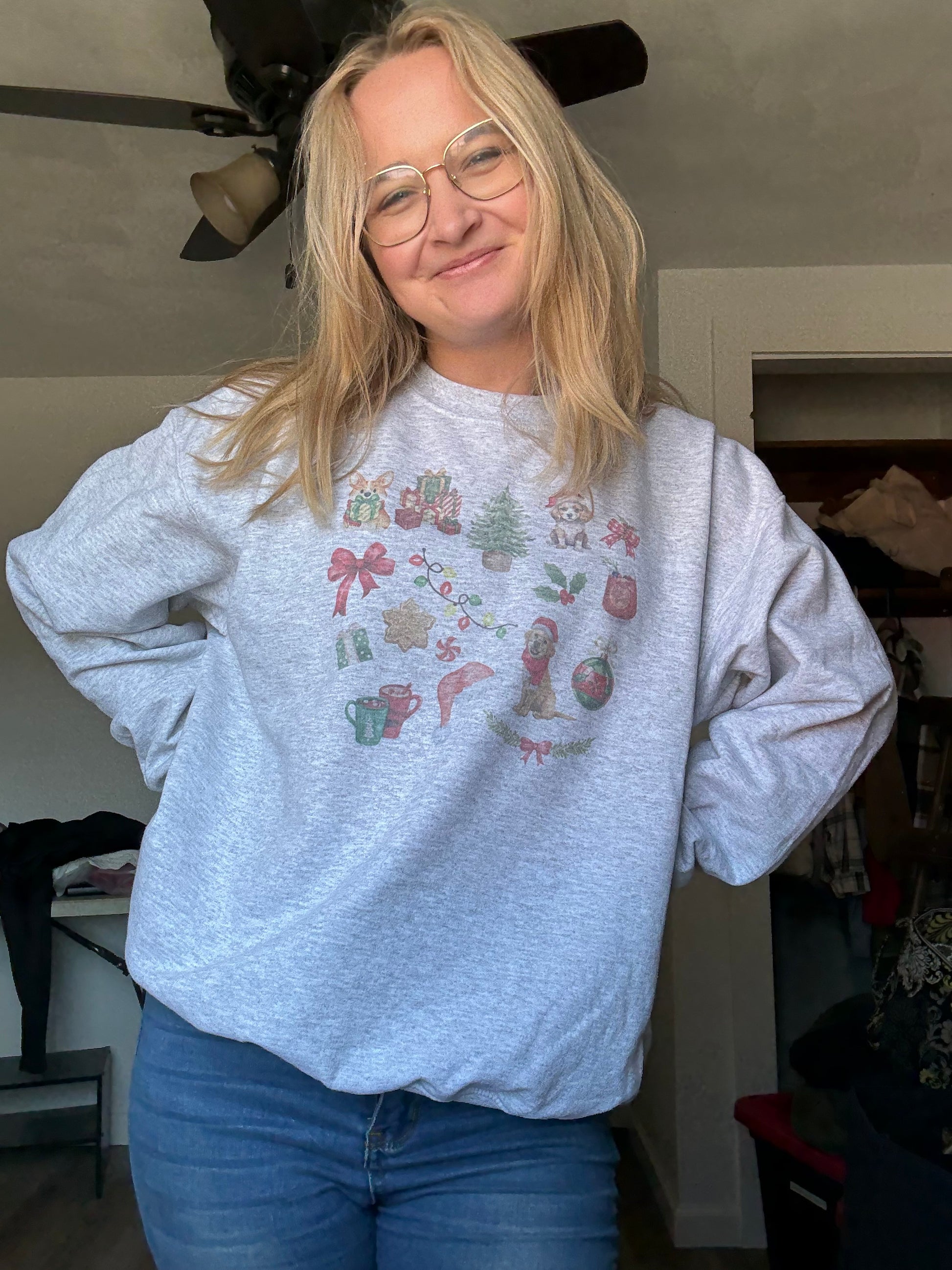 Person wearing watercolor dog Christmas collage sweatshirt in ash gray, Gildan 18000 unisex crewneck for dog parents, cute festive pet-themed holiday top, cozy winter outfit for dog lovers styled with everyday casual clothing.