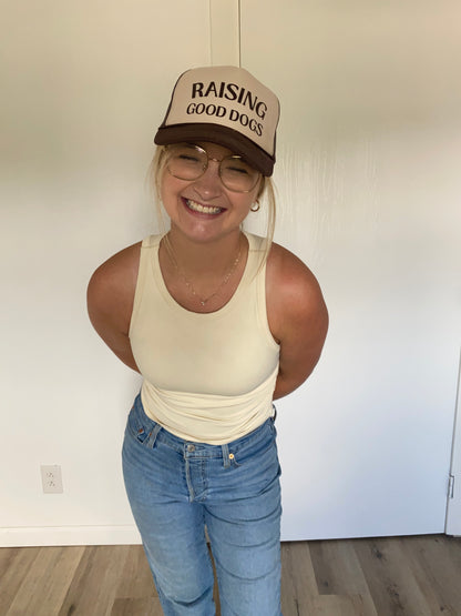 Person wearing a cap with 'Raising Good Dogs' text, smiling indoors.