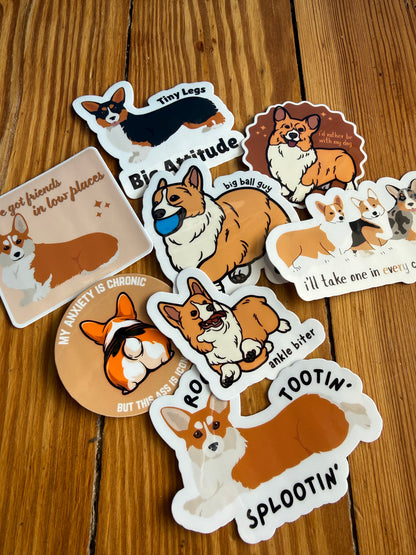 A collection of 8 illustrated corgi-themed stickers spread out on a light-colored wooden floor. The stickers feature various puns, colorful corgi graphics, and playful phrases in a modern, vibrant style.