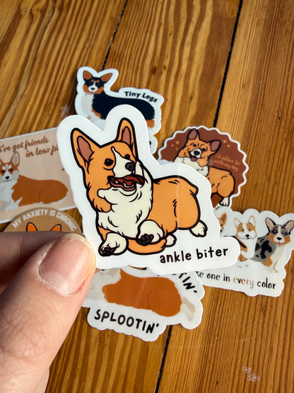 "Ankle Biter": Close-up of a sticker showing a corgi in a fast running pose with the playful text "Ankle biter."