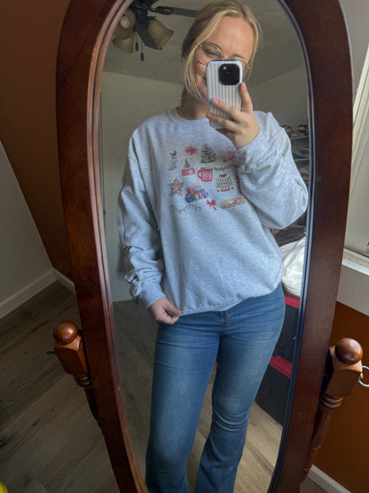 christmas cat watercolor collage sweatshirt worn by girl in jeans taking a mirror selfie, ash gray gildan crewneck featuring artistic holiday cat illustrations, perfect cozy winter outfit for cat moms, long tail christmas cat sweatshirt gift idea for women who love cats