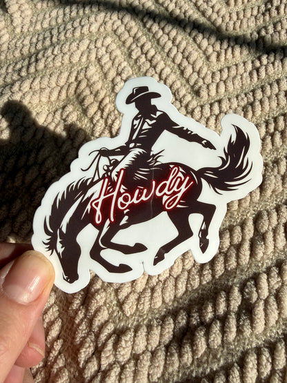 A neon style "Howdy" sticker with a cowboy on a bucking horse; vintage rodeo aesthetic decal, perfect for hydro flasks and laptops.