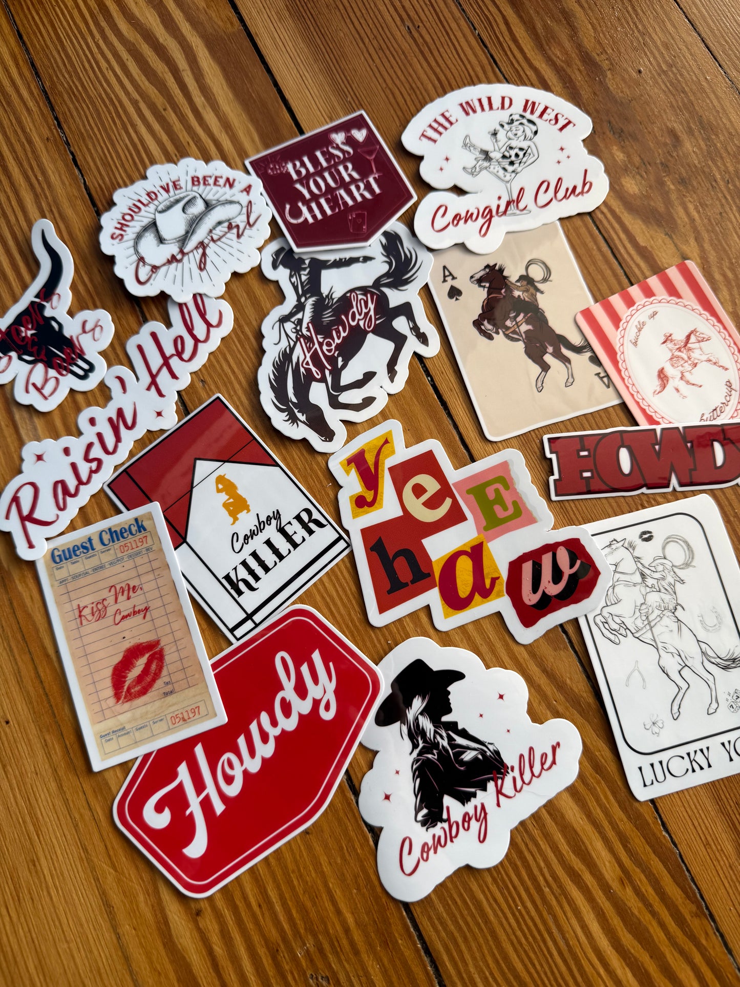 Full set of 15 edgy chic western stickers for water bottles and laptops, featuring pink and red aesthetic cowgirl designs, lucky horseshoe, and retro desert vibes on a light wood background.